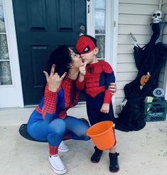 two children dressed up as spiderman kissing each other on the front porch with halloween decorations in the background