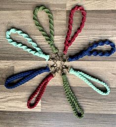 six crocheted lanyards arranged in a circle on a wooden floor, with one loop tied to the end