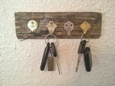 three keys hang on a wooden key holder with four different sized keys hanging from it