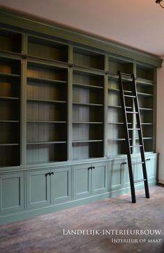 an empty room with green bookcases and ladder