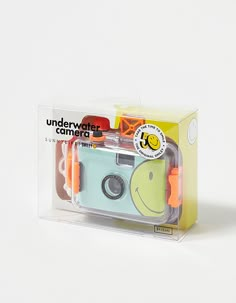 a camera in a clear box on a white surface with an orange and yellow sticker