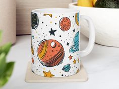 a coffee mug with an image of the planets on it sitting next to some lemons