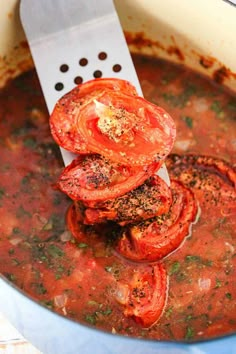 tomatoes being cooked in a pot with a spatula