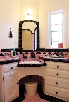 a bathroom with pink and black tiles on the walls, sink, mirror and toilet