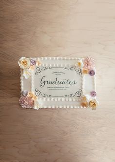 a cake decorated with flowers and the words graduates on it is sitting on a table