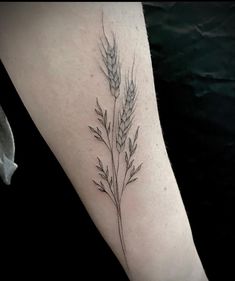 a close up of a person's arm with a plant tattoo on the forearm