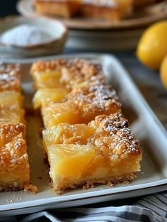 several pieces of pineapple pie on a white plate with lemons in the background