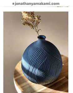 a blue vase sitting on top of a wooden table next to a plant in it