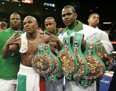 three men standing next to each other holding up their boxing belts in front of them