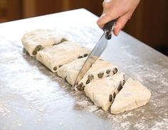 a person cutting bread with a knife on a counter