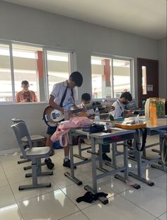 a group of children sitting at desks in a classroom with teacher and two boys