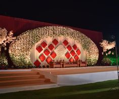 the stage is decorated with flowers and greenery for an outdoor wedding ceremony at night