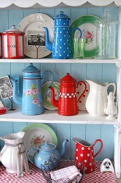 a shelf filled with dishes and teapots on top of a checkered table cloth