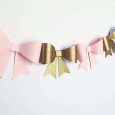 a pink and gold bow banner with metallic foil on the top, hanging from a string