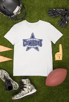 Looking for the perfect Cowboys Football T-shirt to show off your team spirit? Look no further! Our shirts are available in both black and white, making it easy to match your game day outfit. But what sets our shirts apart is the ability to customize the design. If you have any requests or ideas for changes, please reach out to us through the message box before placing your order. We want to ensure that you receive exactly what you're looking for. And if you're in search of a truly unique gift, we can also create a custom design just for you. From personalized gifts for Mom and Dad, to gifts for your boyfriend or husband on their birthday, we've got you covered. Our shirts also make great gifts for boys and football fans of all ages. Our shirts are perfect for vintage football enthusiasts, Team Spirit Tops With Team Name For Tailgating, Football Season Cheerleading Fan Apparel T-shirt, Football Season Cheerleading T-shirt With Team Name, Sports Fan T-shirt With Team Name For Tailgating, Team Spirit Tops For Tailgating, Team Spirit Short Sleeve T-shirt For Tailgating, School Spirit T-shirt For Tailgating With Crew Neck, School Spirit Crew Neck T-shirt For Tailgating, School Spirit T-shirt For Tailgating