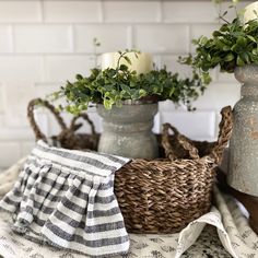 three vases with plants in them sitting on a table cloth next to some candles