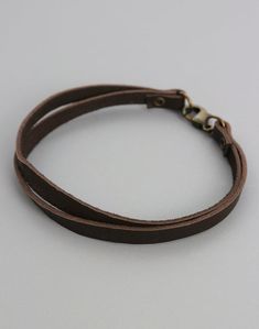 a close up of a leather bracelet on a white surface