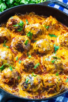 a skillet filled with meatballs covered in cheese and parsley on top of a checkered table cloth