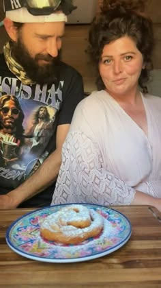 a man and woman sitting at a table with doughnuts in front of them