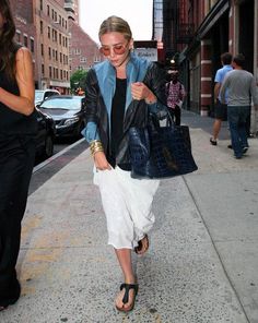 a woman walking down the street carrying a purse