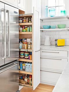 an organized pantry in a kitchen with white cabinets and stainless steel appliances, including a refrigerator