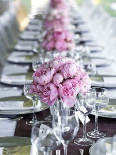 a long table is set with pink flowers and silverware for an elegant wedding reception