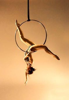 a woman is doing aerial acrobatics on a hoop