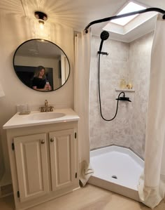 a woman taking a photo in the mirror of a bathroom with a shower and sink