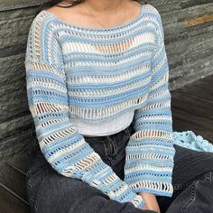 a woman sitting on a wooden bench wearing a blue and white striped knitted sweater