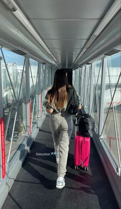 a woman is walking down the walkway with her luggage