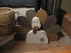 a wooden turkey sitting next to a coffee cup