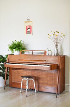 a piano sitting on top of a hard wood floor next to a potted plant