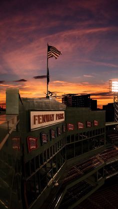 fenway park at sunset with an american flag on the roof and lights in the background