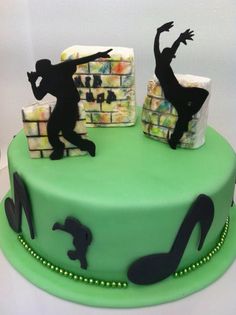 a green cake with black silhouettes of people dancing on top of blocks and music notes