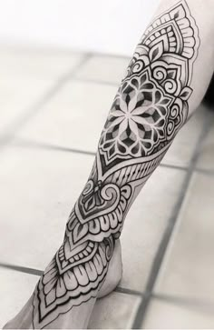 a black and white photo of a person's leg with an intricate tattoo design on it