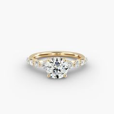 a yellow gold engagement ring with three stones on the band and a round center stone