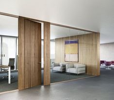 an office with glass walls and sliding doors that open up to the meeting room area