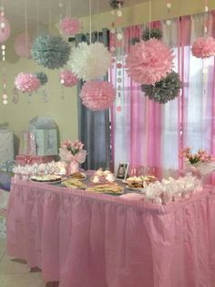 a table with pink and silver decorations hanging from it's ceiling in front of a window