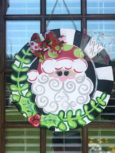 a christmas wreath hanging on the side of a window with santa's face painted on it