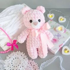 a pink teddy bear sitting on top of a table next to lace doily and other items