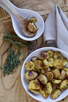 two white bowls filled with cooked potatoes on top of a wooden table