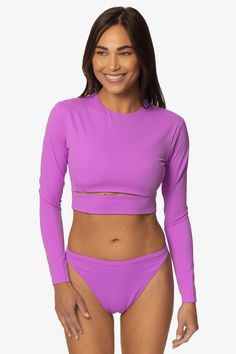 " Rashguards have never looked so good till now. The Taranaki women's rashguard is perfect for being out in the water or down the boardwalk. Featuring a stylish cut out the Taranaki rashie is perfect for those looking for fashion and function. You'll be wearing this cropped rashie from sunrise to sunset. You won't need to wear another top underneath this rashie, the Taranaki is double-lined for privacy and has an elastic underbust to keep you supported. Suit up and charge the day. Features: Good Fitted Surfing Tops With Upf 50+, Upf 50+ Crew Neck Swimwear, Crew Neck Swimwear With Upf 50+, Fitted Long Sleeve Tops For Water Sports, Summer Beach Crew Neck Rash Guard, Summer Beach Rash Guard With Crew Neck, Long Sleeve Tops For Summer Water Sports, Long Sleeve Tops For Water Sports In Summer, Fitted Long Sleeve Tops With Uv Protection