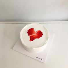 a white cake with a red heart painted on it