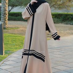 Indulge In The Allure Of Our Beige Striped Modern Abaya, A Perfect Blend Of Sophistication And Fashion-Forward Design. Crafted From Dubai's Renowned Cey Fabric, This Abaya Exudes Elegance And Comfort. Here's Why It's A Must-Have In Your Wardrobe: Key Features: Chic Bell Sleeves: Embrace A Trendy Silhouette With Our Bell Sleeves, Adding A Touch Of Modernity To Your Look. Contrasting Black Strips: The Sleek Black Strips On The Sleeves And Kimono-Style Mandarin Collar Create A Striking Contrast, El Cream Long Abaya For Eid, Cream Abaya For Eid, Beige Long Thobe For Eid, Cream Long Sleeve Thobe For Eid, Long Sleeve Cream Thobe For Eid, Modest Beige Hijab For Eid, Abaya With Hijab, Lace Kaftan, African Kaftan