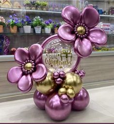 purple and gold balloon flowers are on display in a flower shop with an award plaque