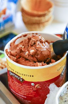 an ice cream sundae bar with chocolate frosting in a cup and spoon on the side