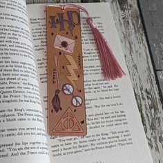 a bookmark with harry potter symbols on it and a tassel hanging from it