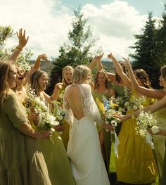 a group of women standing next to each other holding bouquets in their hands and smiling