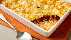 a casserole dish with meat and vegetables in it on a wooden cutting board