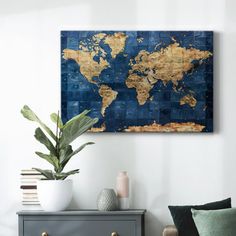 a blue and gold world map on the wall above a gray dresser with two white vases